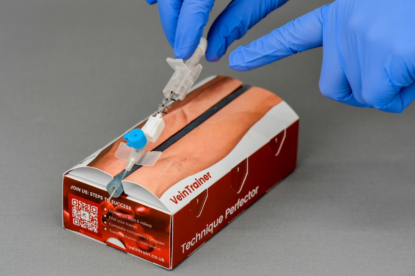 Gloved hands practising IV cannulation on a simulation vein pad, where early complications can be safely recognised.